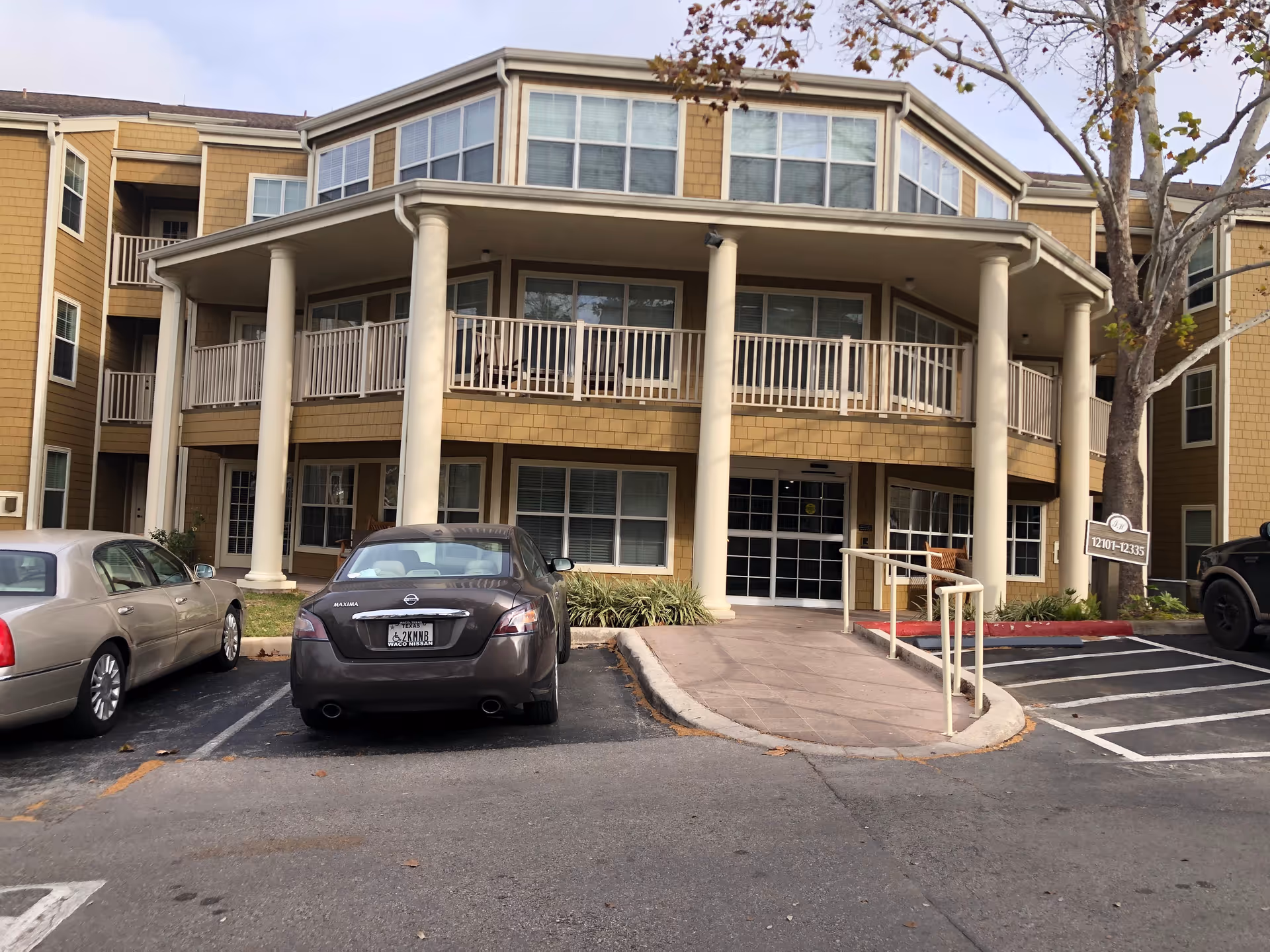 Front view of Independence Hill Assisted Living building with columns, balconies, and parked cars.