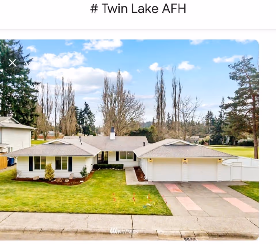 Single-story white house with attached garage, front lawn and driveway under a blue sky.