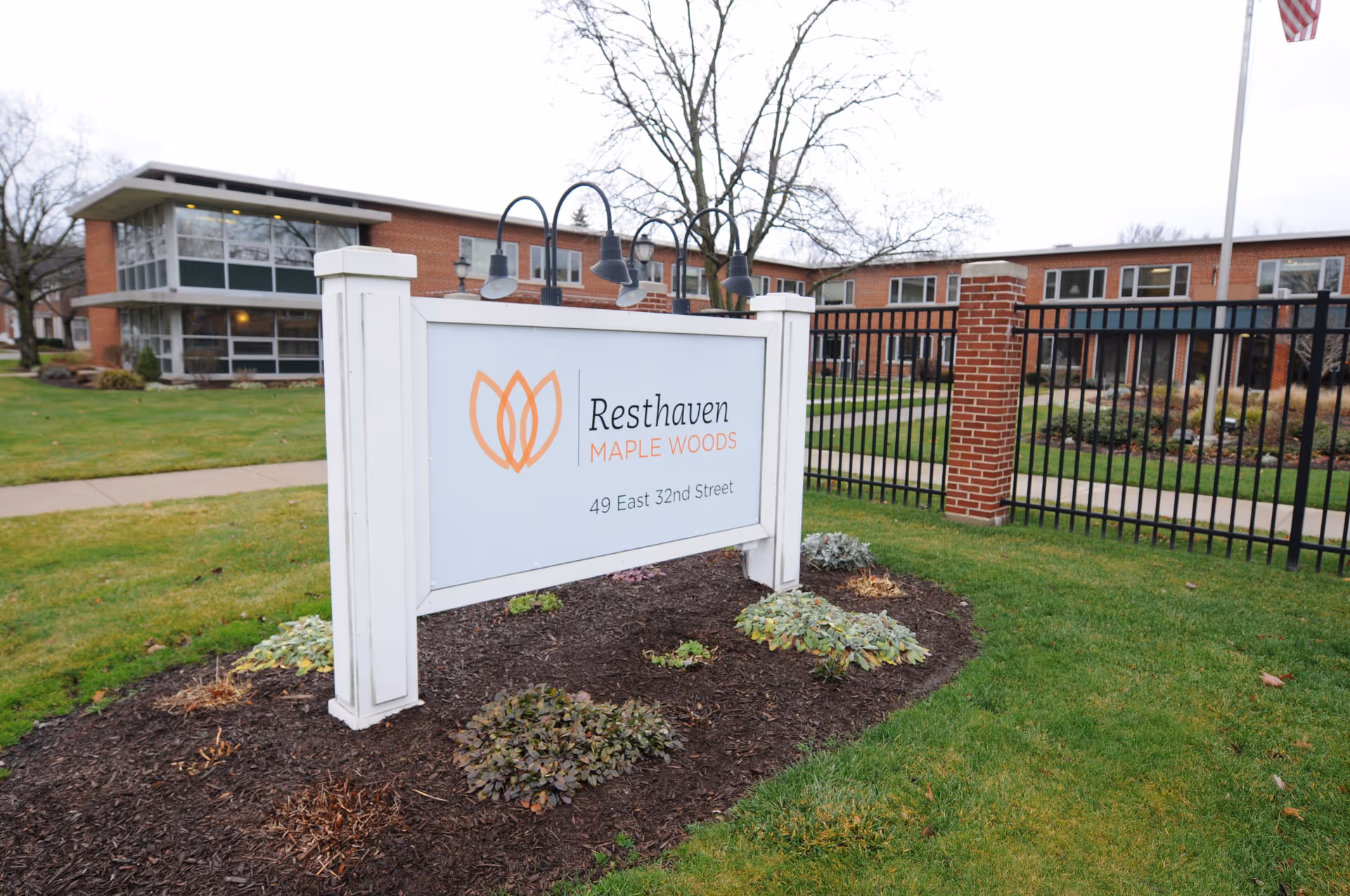Exterior view of Resthaven Maple Woods with a white sign, lawn, and brick building.