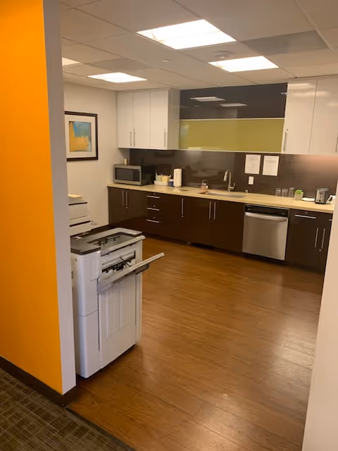 Modern kitchenette in a senior living facility with cabinets, sink, and appliances.