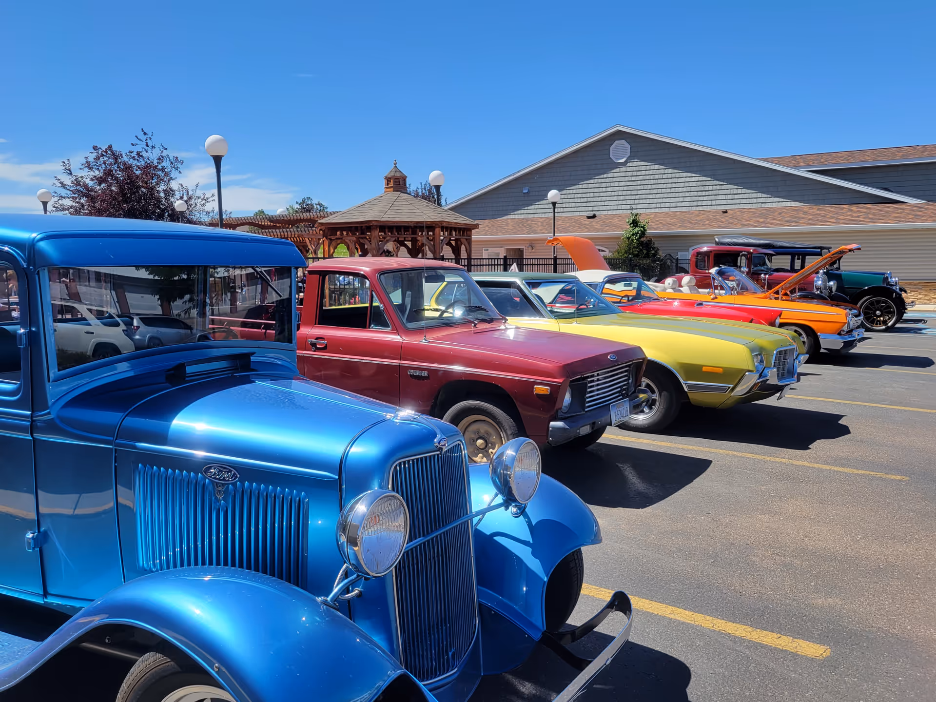 Row of colorful vintage cars parked in front of BeeHive Homes of Great Falls exterior.