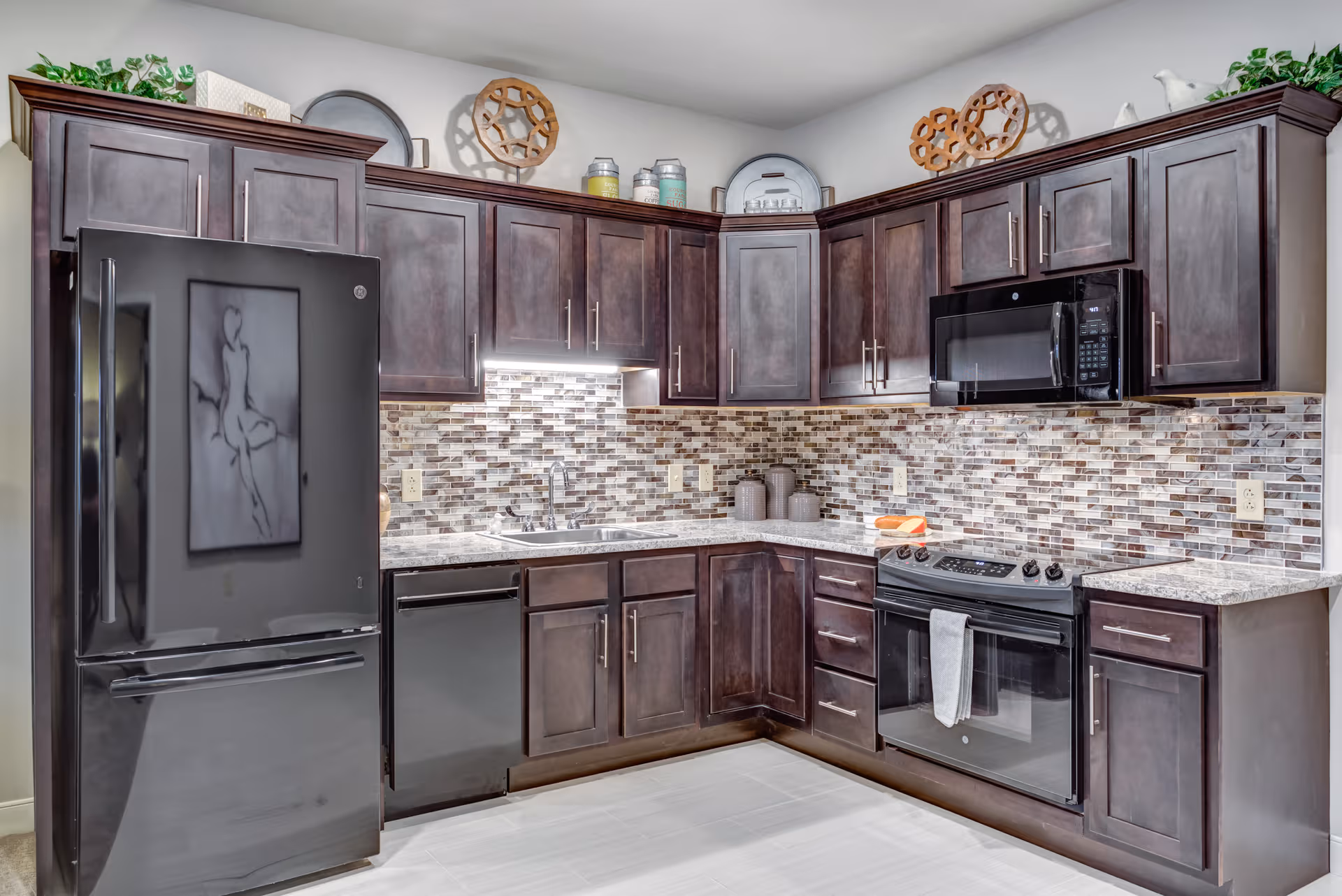 A modern U-shaped kitchen with dark cabinets, stainless appliances, and tiled backsplash.