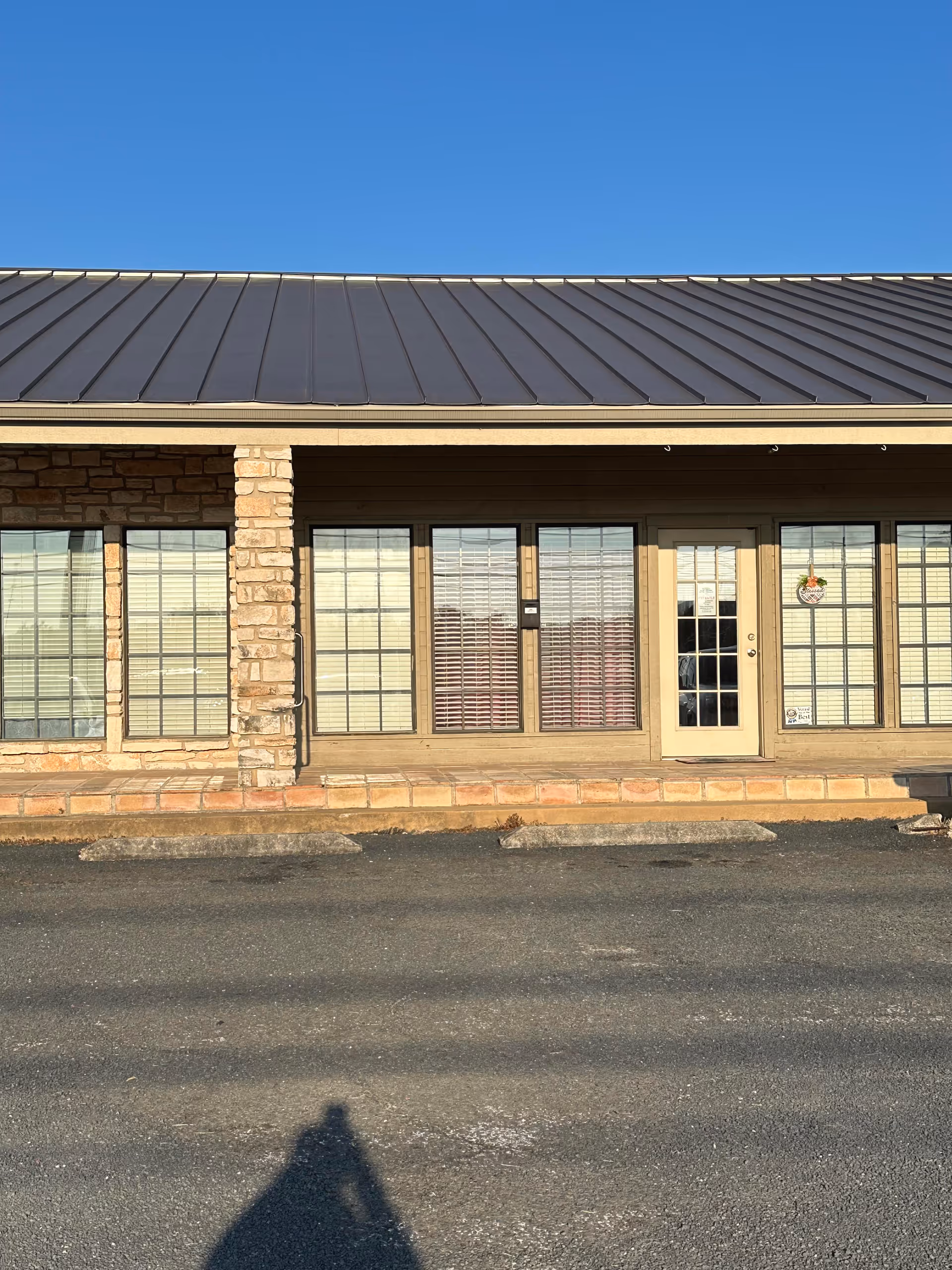 Front view of a single-story building with large windows and a metal roof.