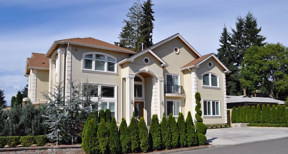 Front view of a cream-colored senior living facility with well-manicured hedges.