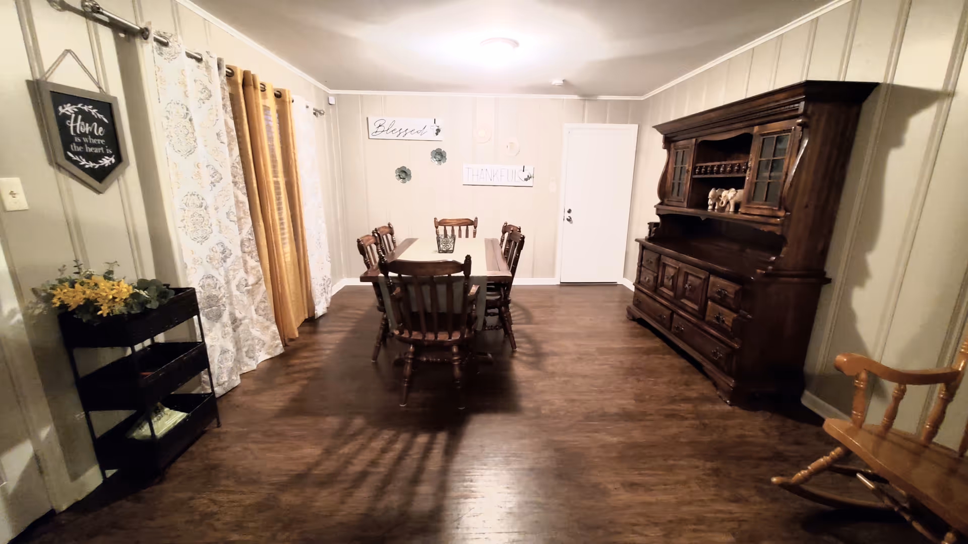 A cozy dining room with a wooden table, chairs, and a large dark china cabinet.