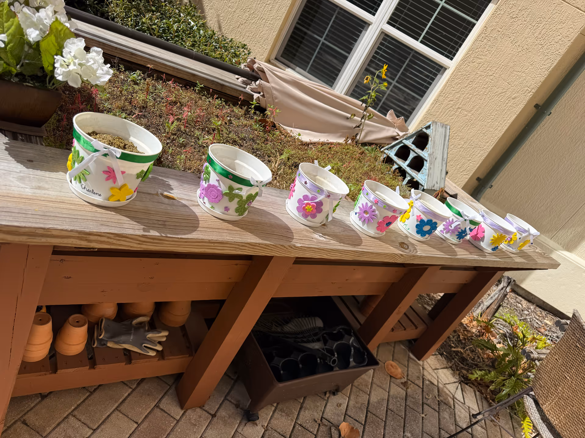 Row of colorful painted flower pots lined along a wooden outdoor table.