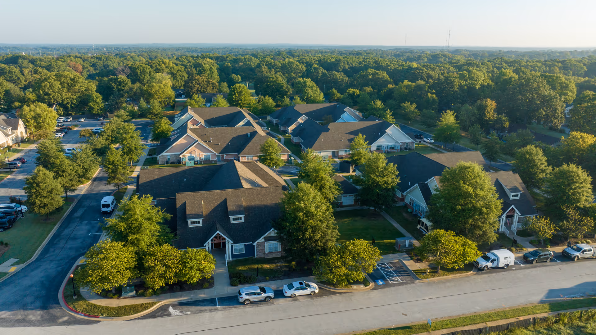 Aerial view of Legacy Village senior living campus with brick buildings and green trees.