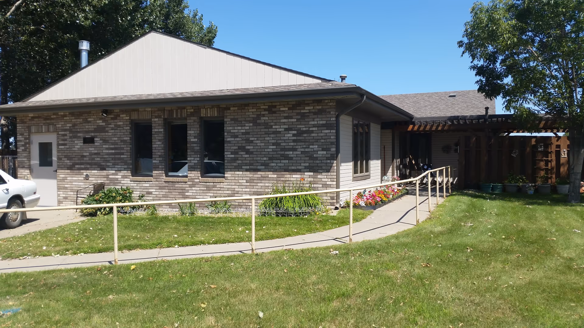 Exterior view of a single-story brick senior living facility with a ramp and garden.