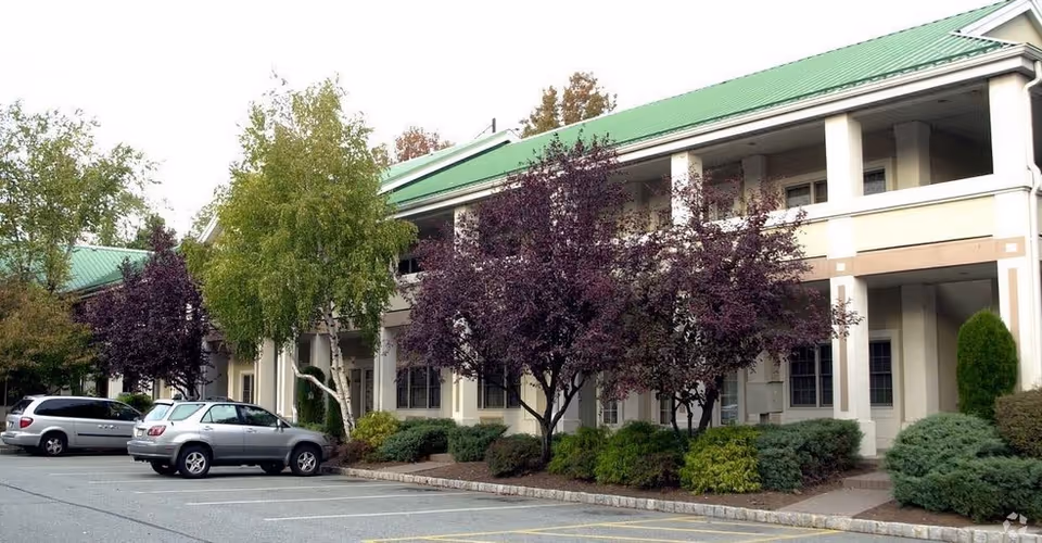 Exterior view of Affinity Home Care facility with a green roof, cars, and landscaping.