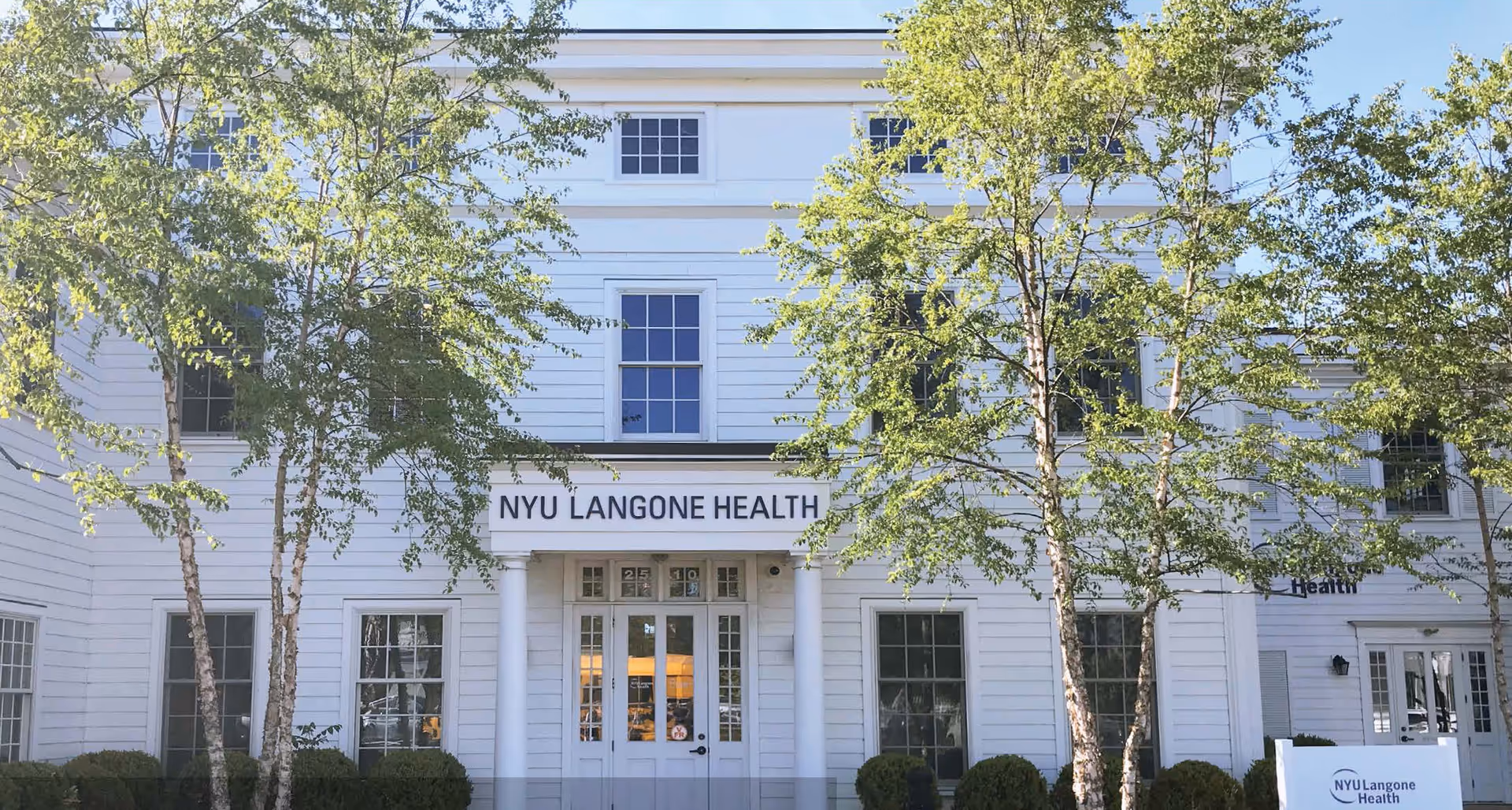 White multi-story building exterior with columns and NYU Langone Health sign.