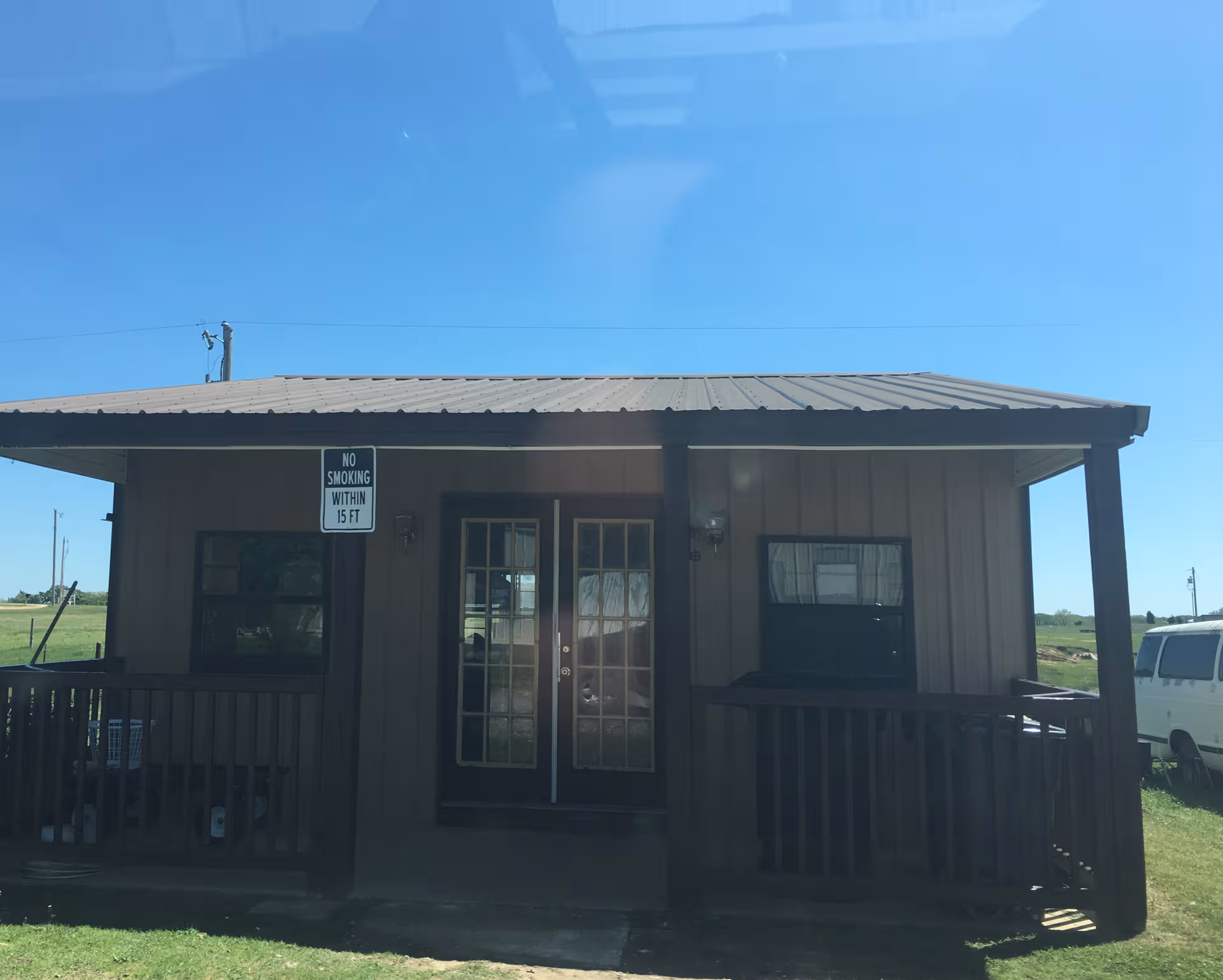 Small brown building with front porch, double doors, and no smoking sign.