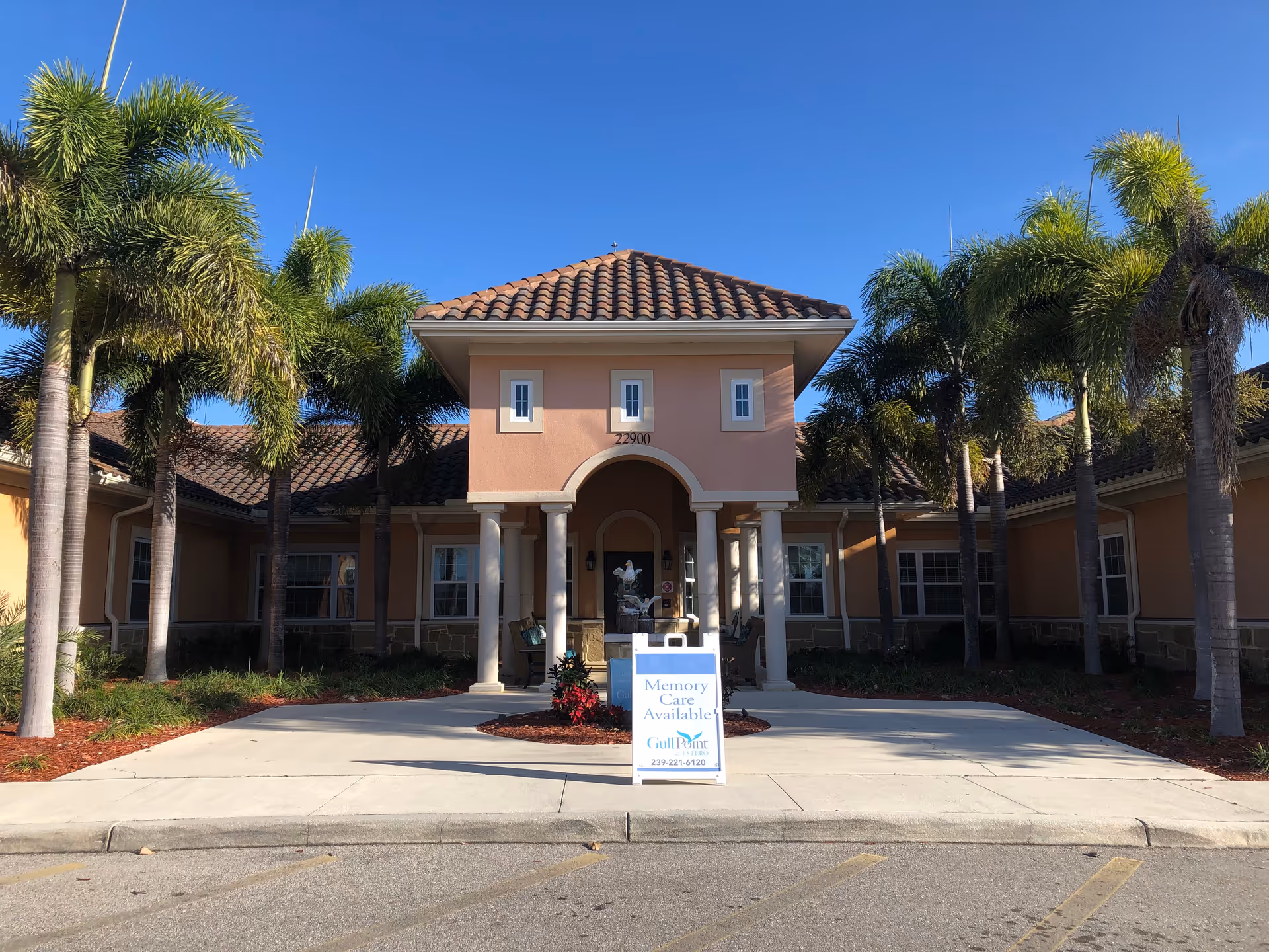 Front view of Gulf Coast Memory Care building with palm trees and driveway.