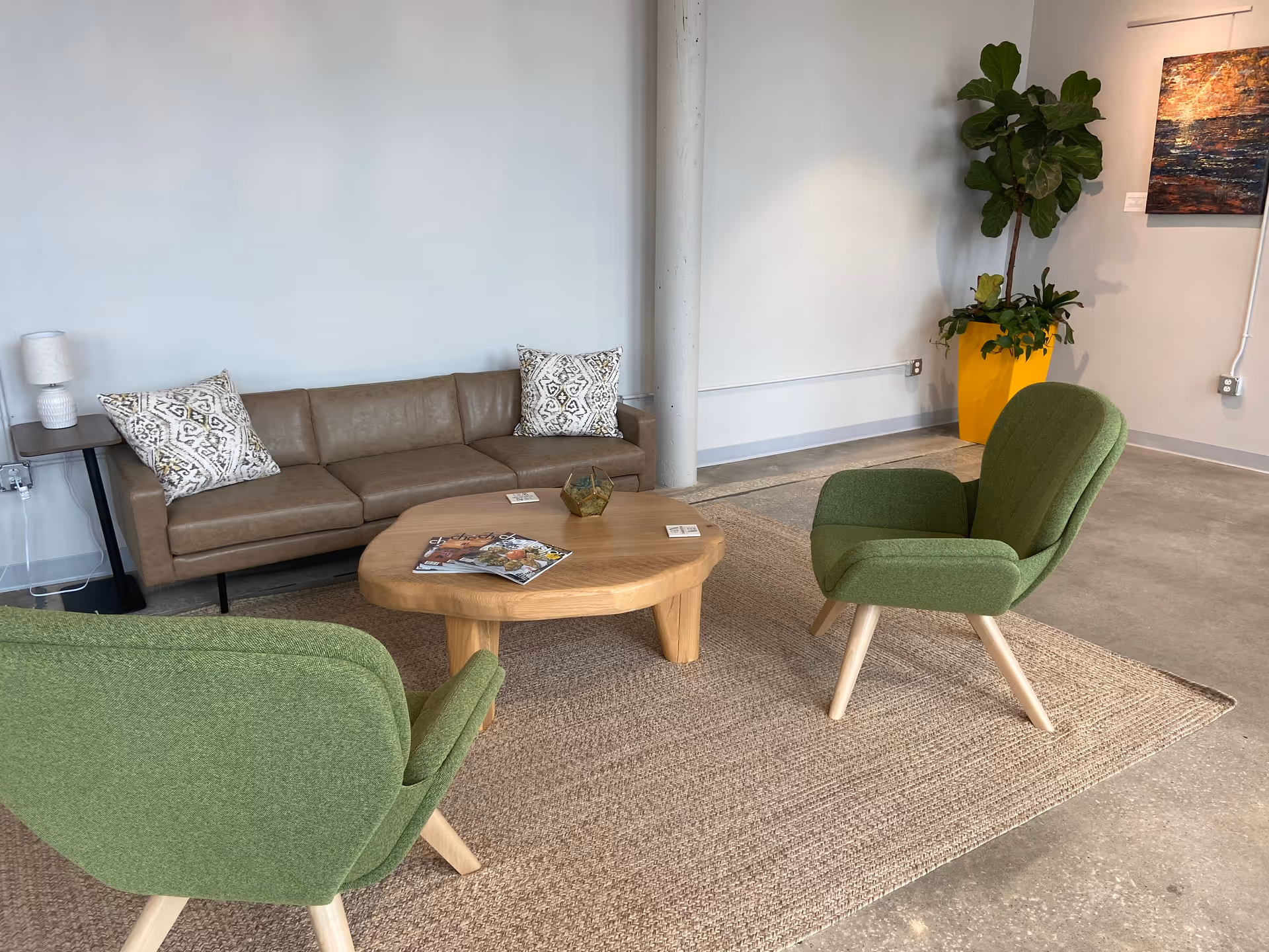 Cozy communal living area with green chairs, a leather sofa, and a round wooden coffee table.
