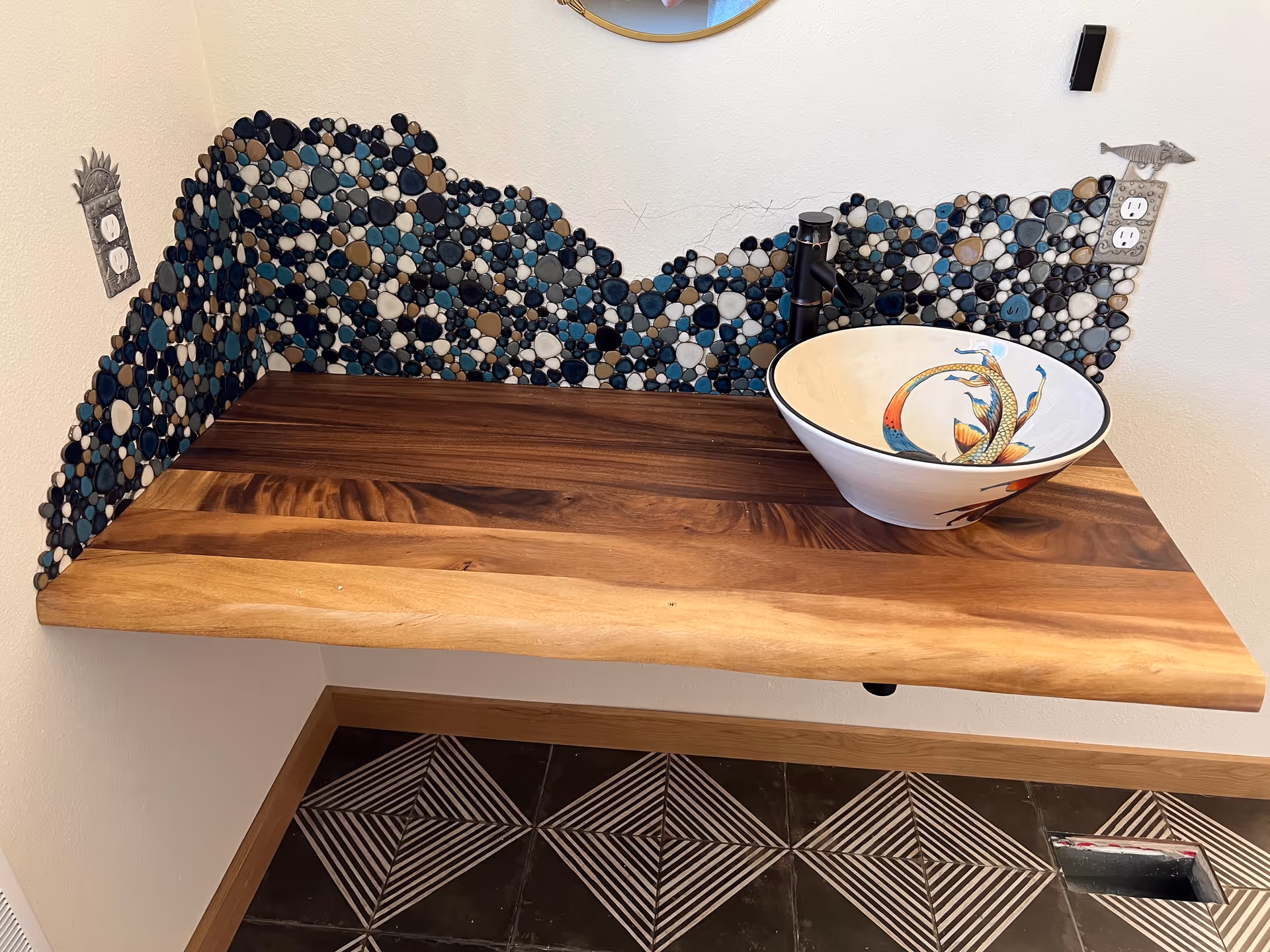 Wooden bathroom vanity with a ceramic bowl sink and mosaic tile backsplash.
