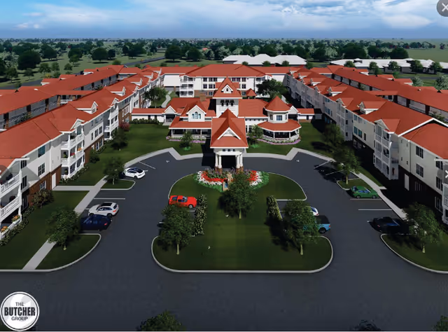 Aerial view of a large senior living complex with red-tiled roofs surrounding a landscaped central circular drive and entrance.