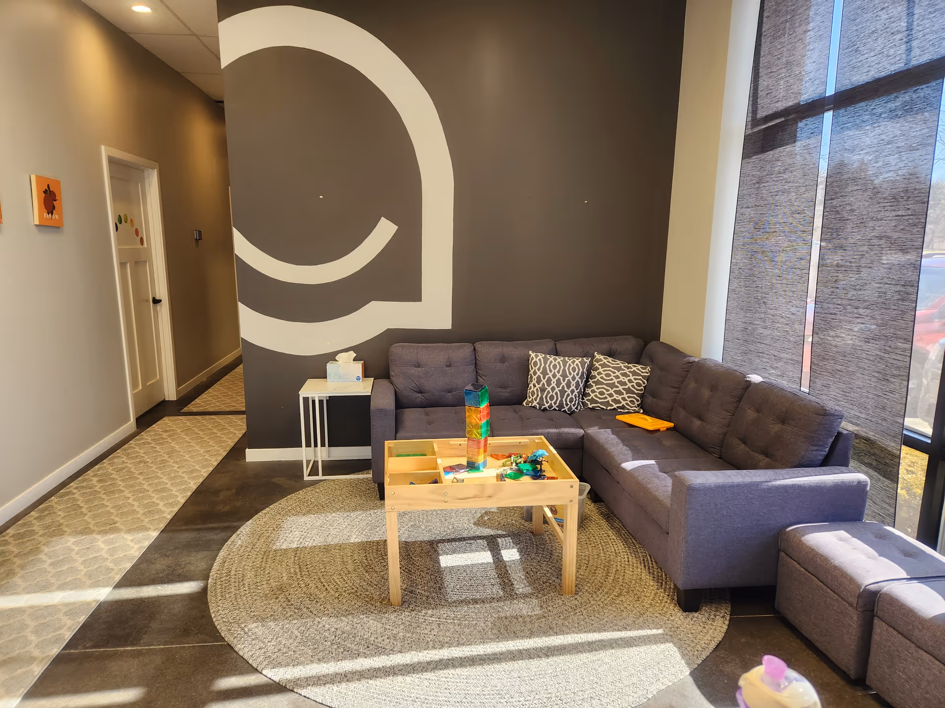 Cozy lounge area with a gray sectional, coffee table, rug, and large wall art.