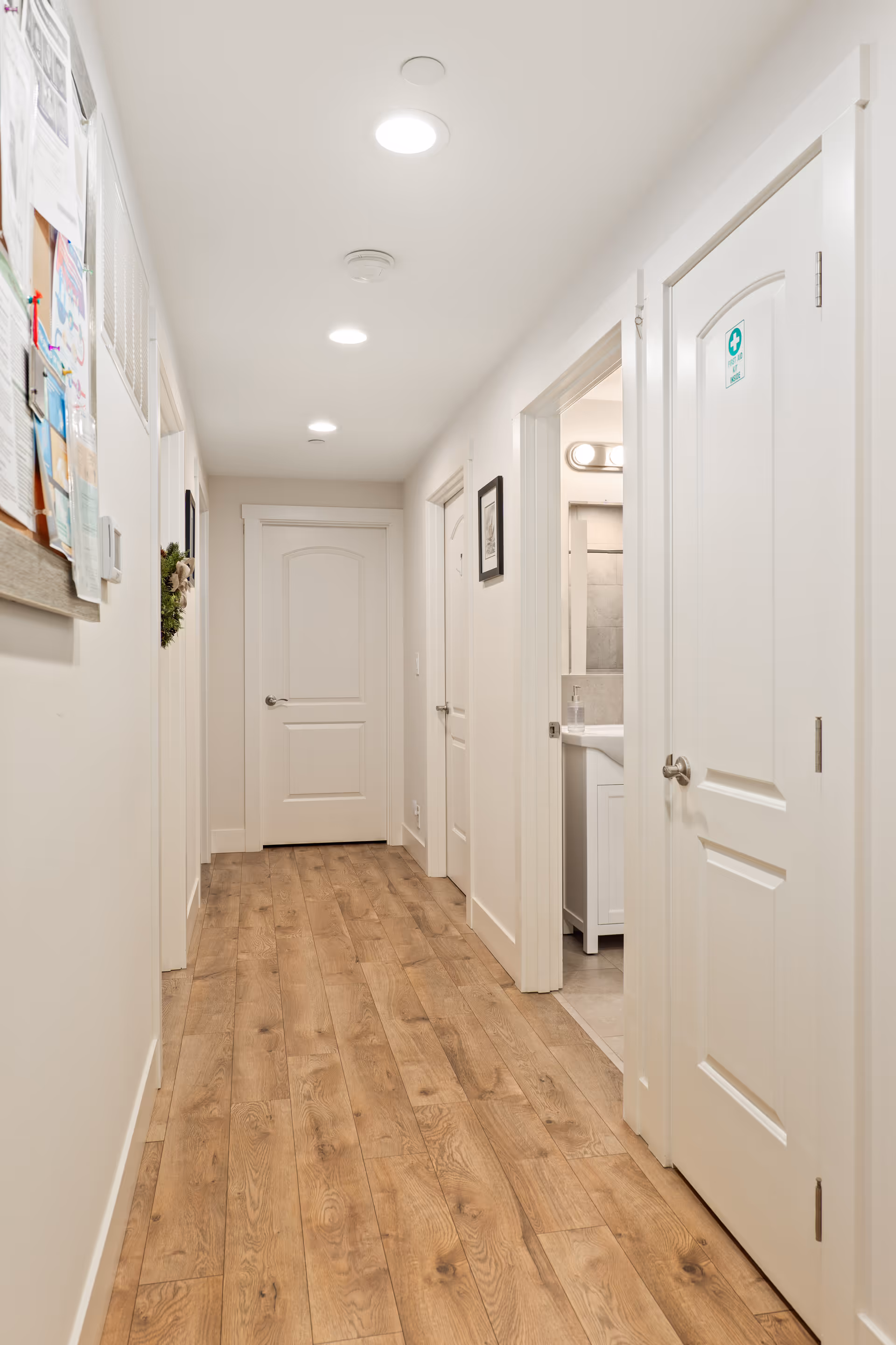 Bright white hallway with doors on both sides and a small bathroom visible.