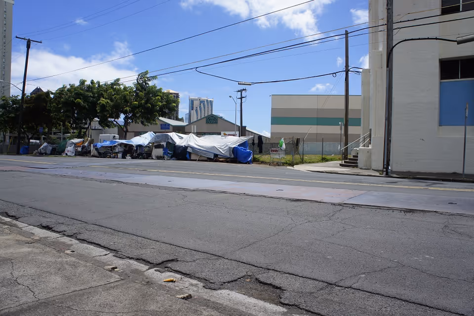 Street view shows tents along the sidewalk beside a large building.
