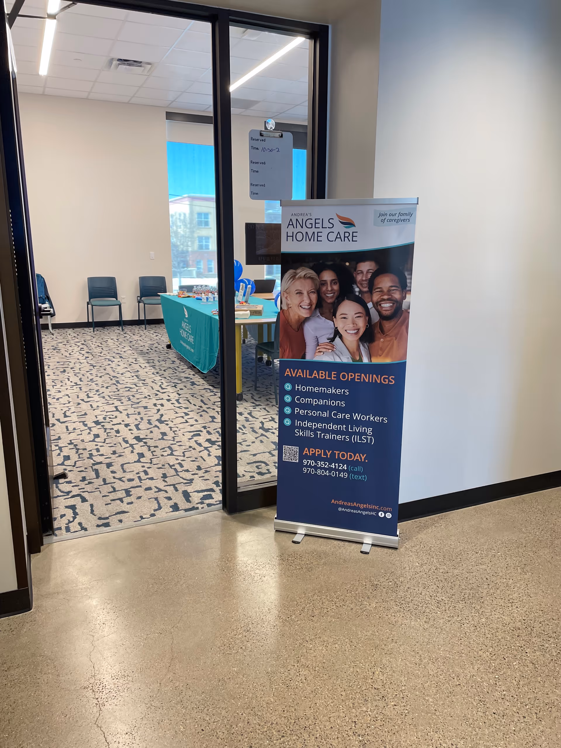 Interior entrance area with standing banner advertising Andrea's Angels Home Care near a doorway.