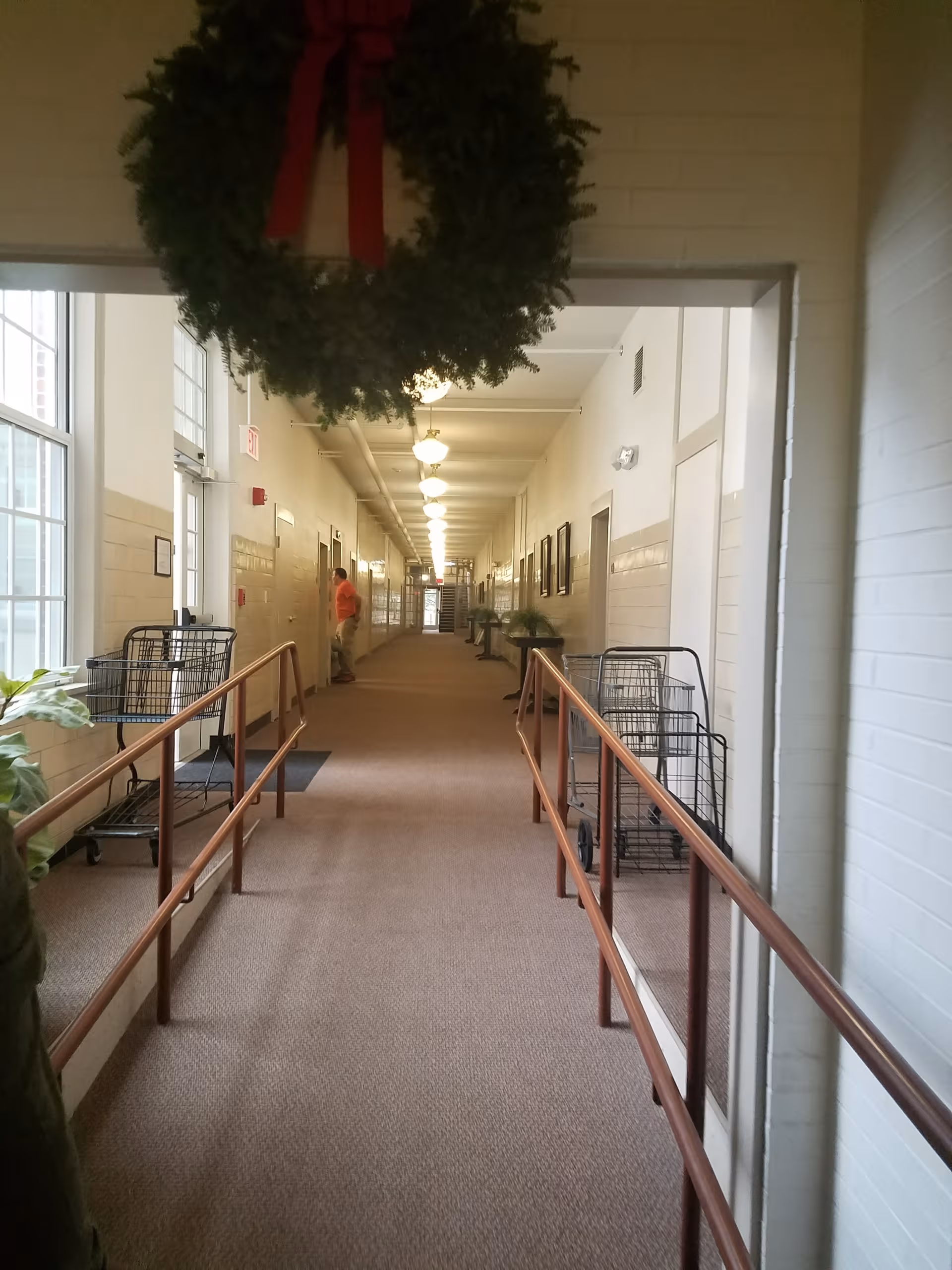 Long interior hallway of a senior living facility with handrails and carts.