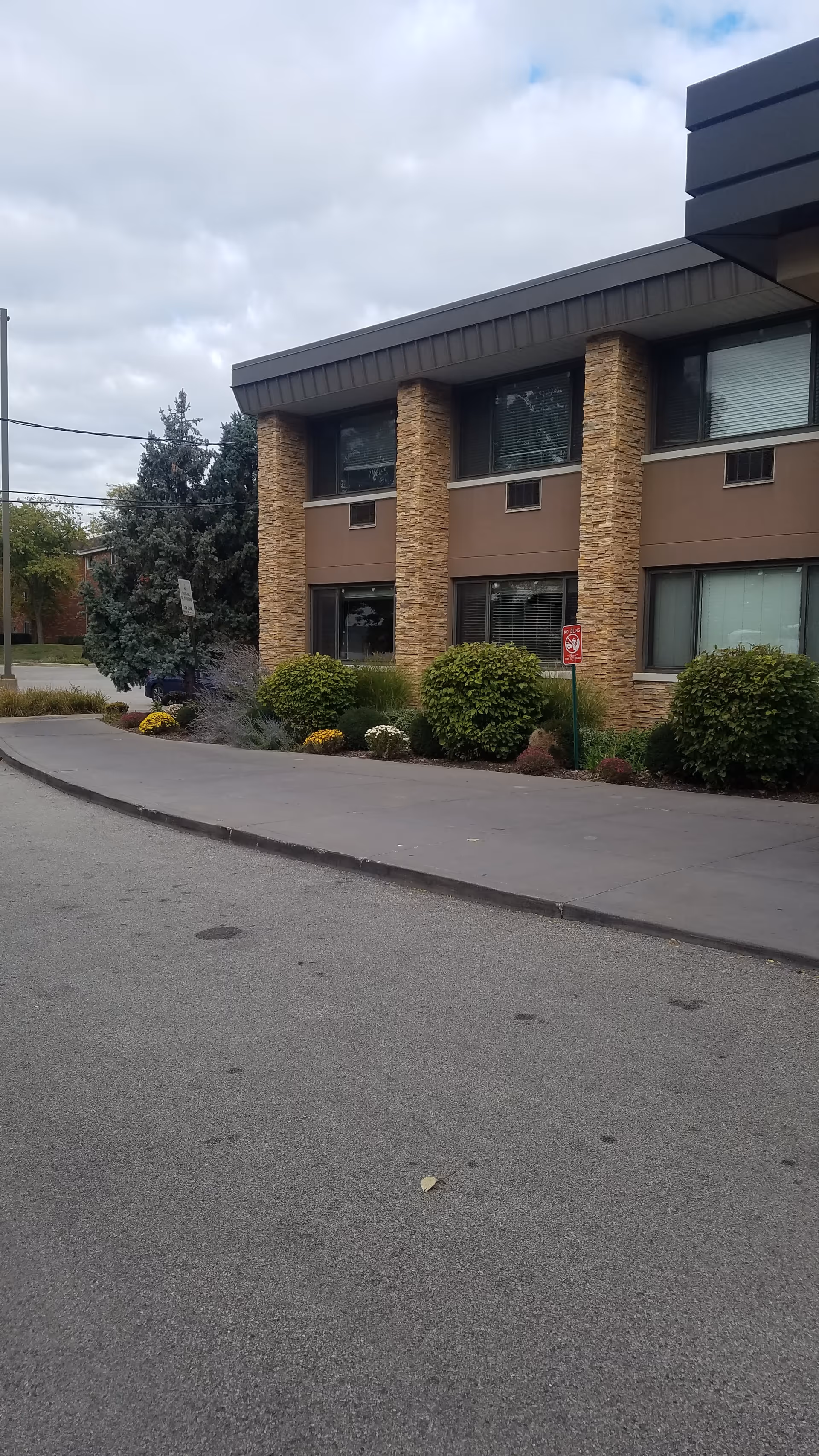 Exterior view of Elevate Care North Branch featuring brick columns, windows, and landscaped shrubs.