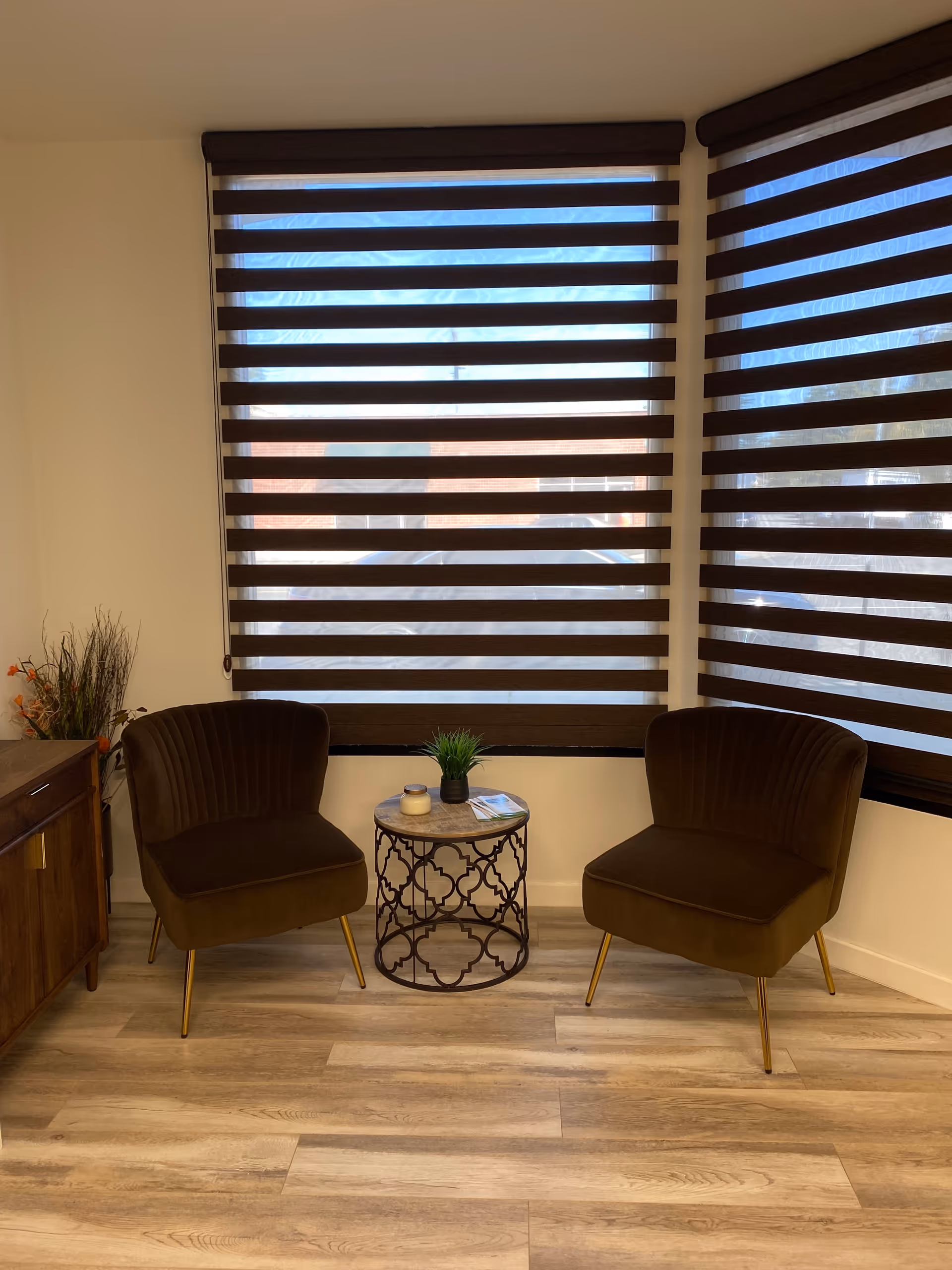 Two brown upholstered chairs flank a small round table in a cozy living area.