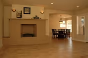 Open living room with a brick fireplace, tiled floor, and a dining table visible through an archway.