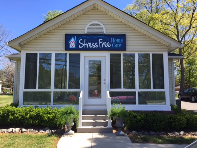 A single-story care facility with large windows and a sign reading Stress Free Home Care.