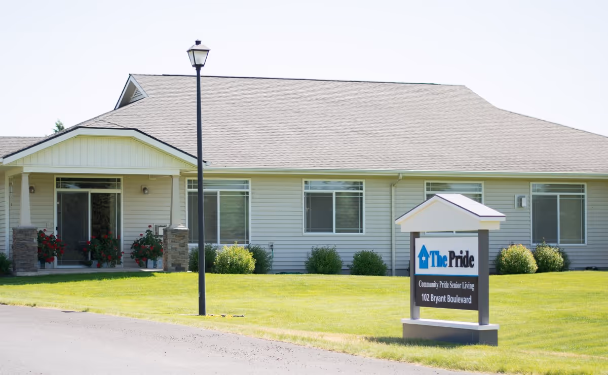 Single-story care home with a manicured lawn, entrance porch, and a sign in front.