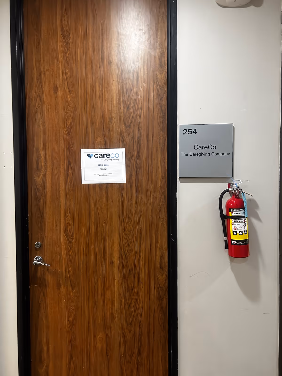 Wooden door with CareCo signage and a fire extinguisher on the wall.