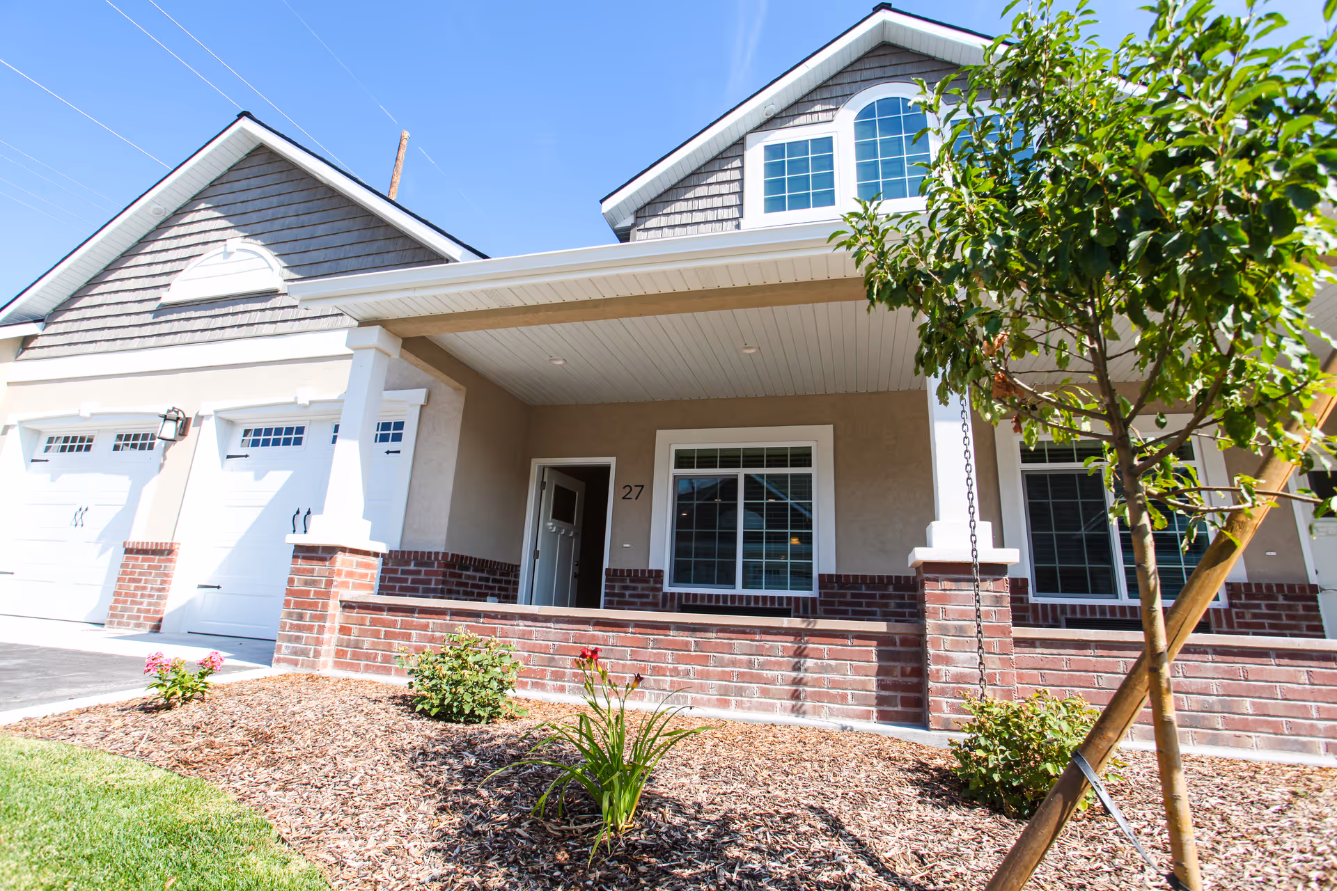 Exterior view of a senior living facility with a covered porch and brick accents.