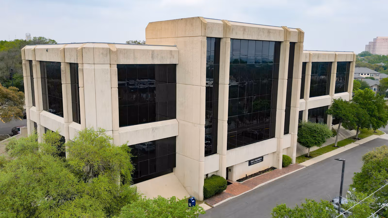 Modern beige building with large black-tinted glass windows, exterior view.