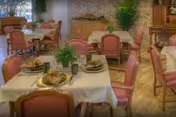 Dining room in a senior living facility with set tables and pink chairs.