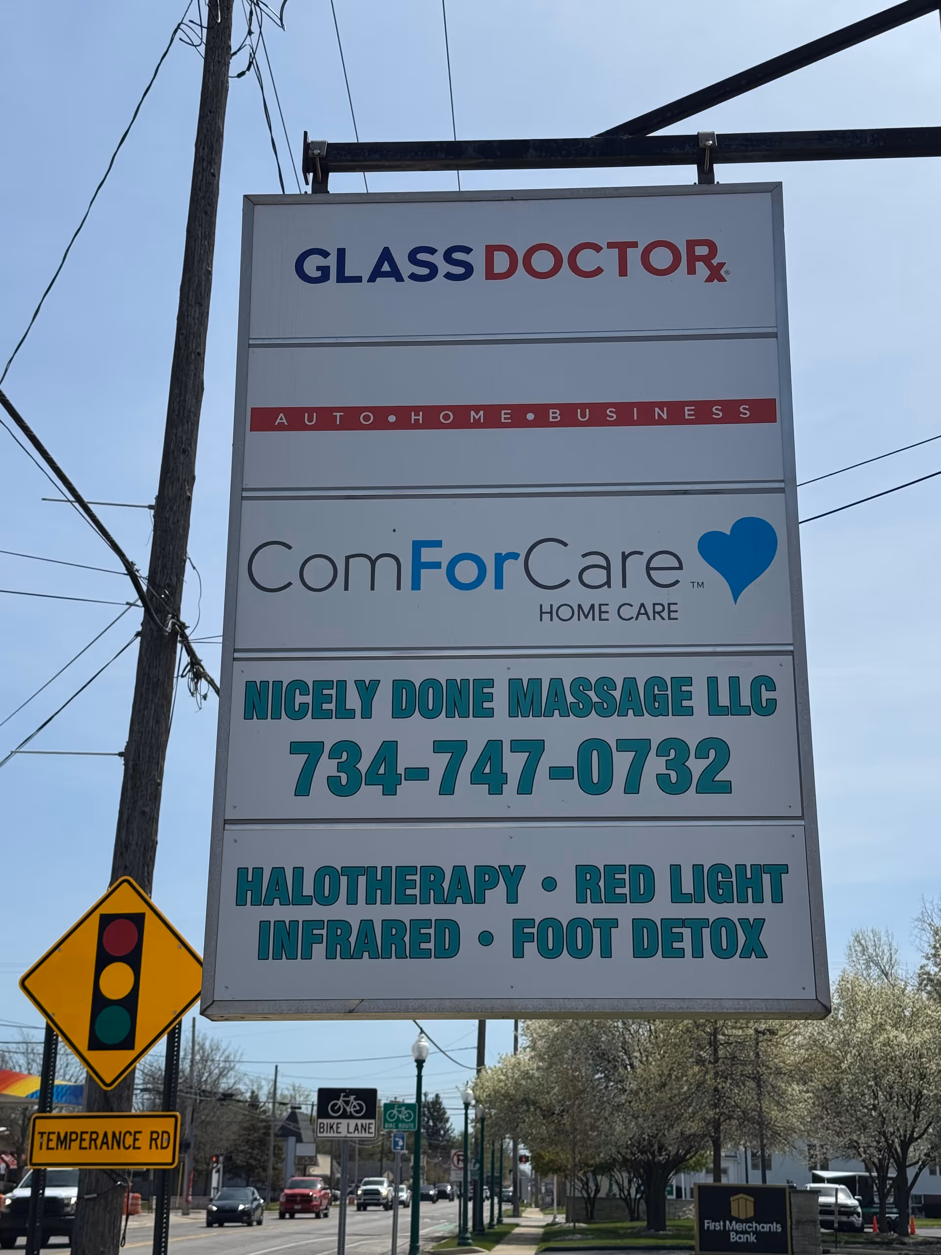 Tall outdoor signboard on a street lists Glass Doctor and ComForCare among others.
