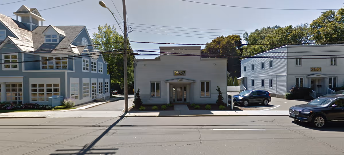 Exterior view of Tutela Services LLC facility along a street with parked cars.