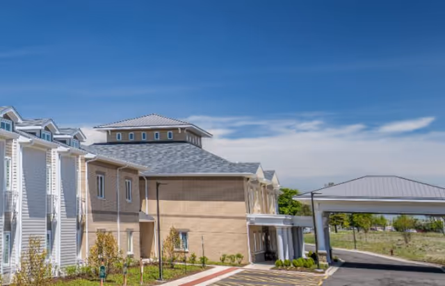 Exterior view of a senior living facility with a covered entrance and parking.