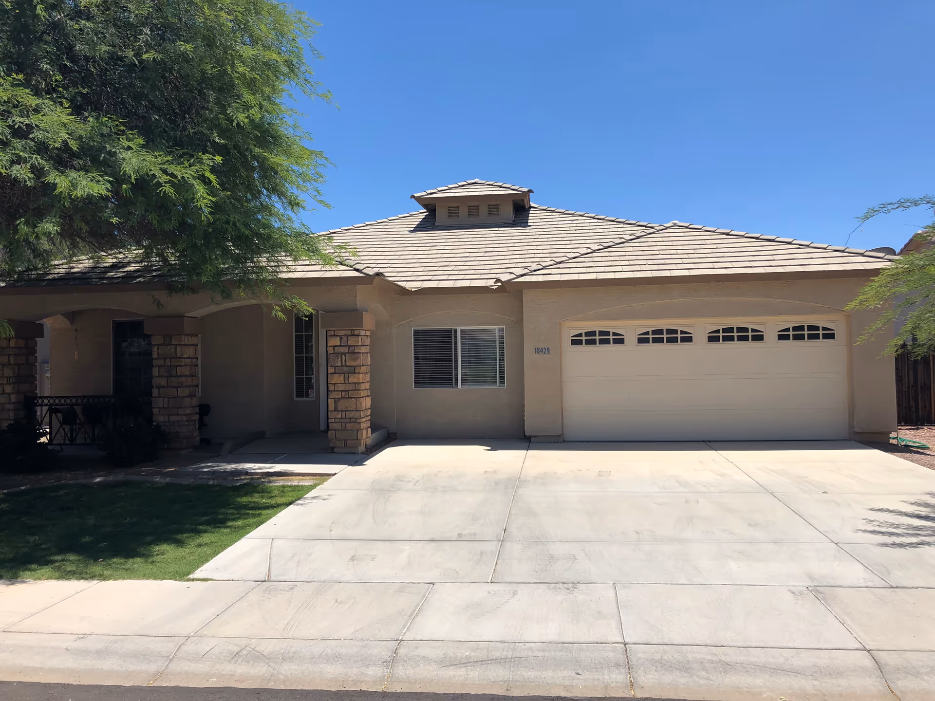 Front view of a single-story beige house with a two-car garage and driveway.