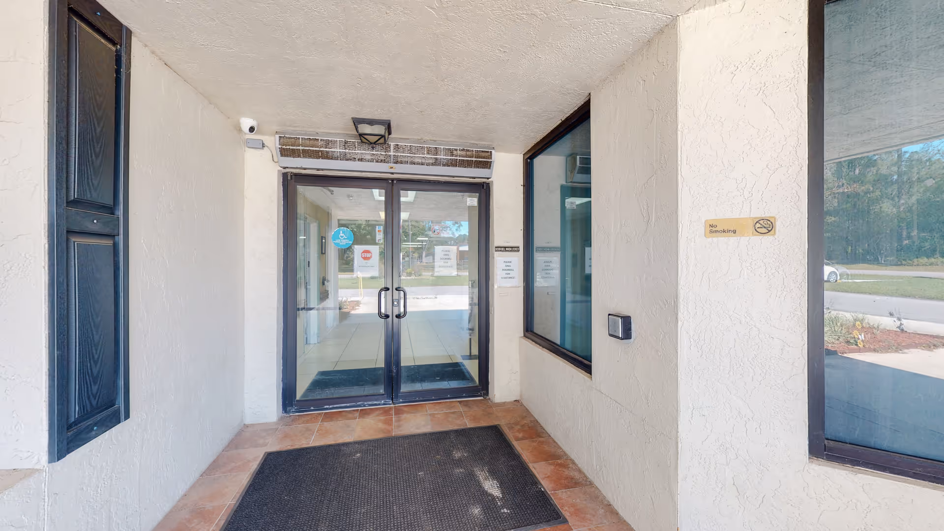 Entrance to a senior living facility with glass doors and white stucco walls.