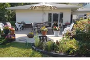 Outdoor patio of a Washington Heights senior living facility with chairs, tables, umbrella, and potted plants.