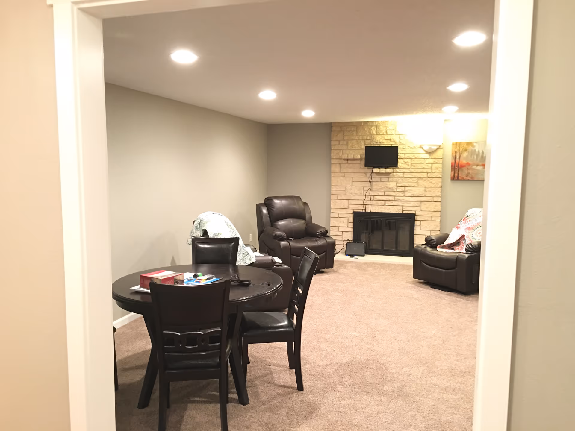 Cozy lounge with leather chairs, a round dining table, and a fireplace.