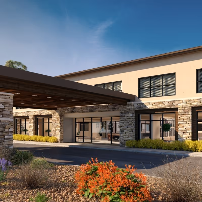 Exterior view of Carnegie Heights at Henderson with stone facade and glass entrance.