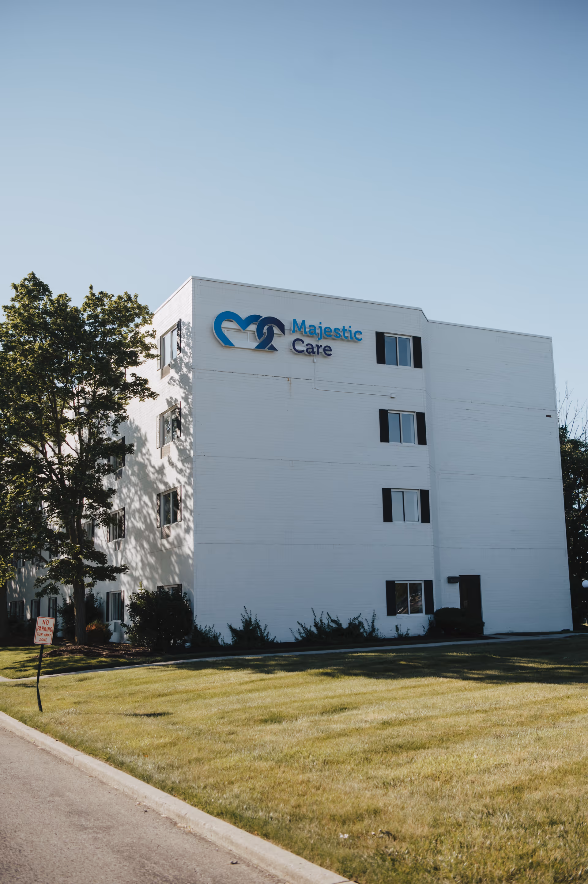 White three-story senior care building with Majestic Care sign and blue logo.