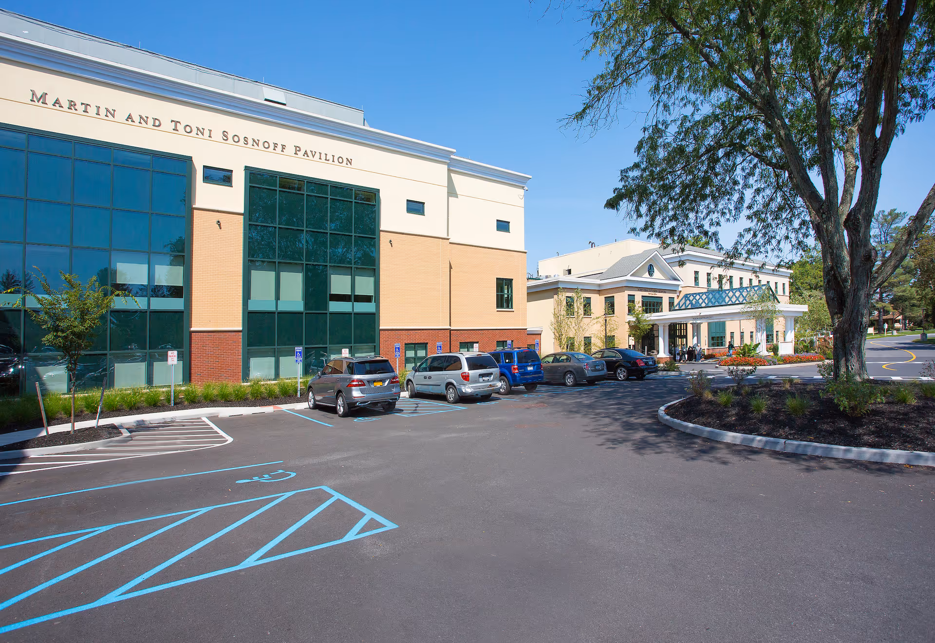 Exterior of Martin and Toni Sosnoff Pavilion with a glass-front entrance and parked cars.