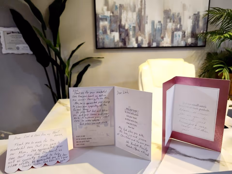 Greeting cards displayed on a white table in a lobby with plants.