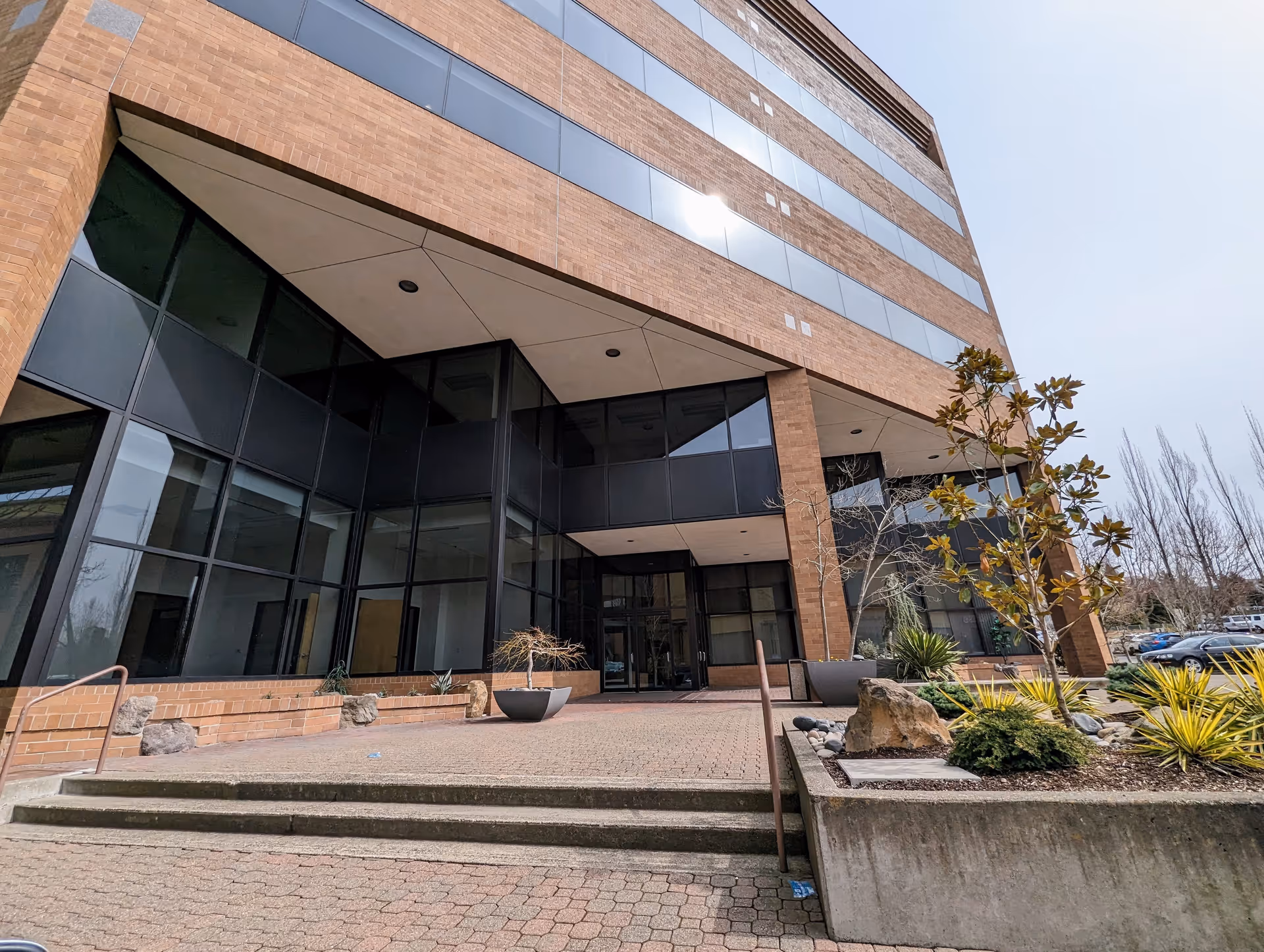 Modern brick building with glass entrance and landscaped front, no people present.