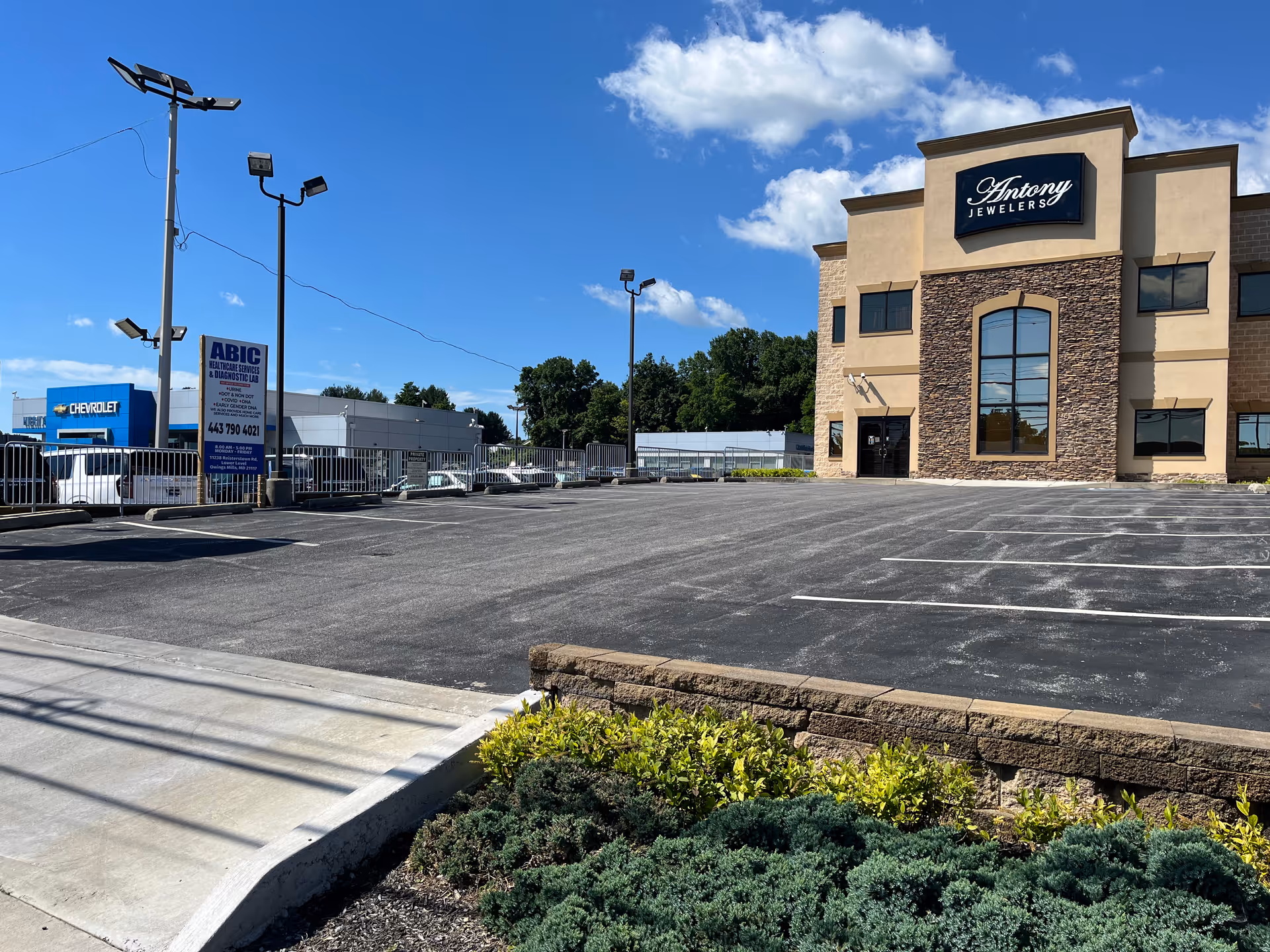 Exterior view of a beige, stone-accent building with signage and a vacant parking lot.