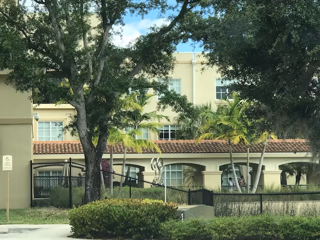 Exterior view of MorseLife Health System building with trees, windows, and a fence.
