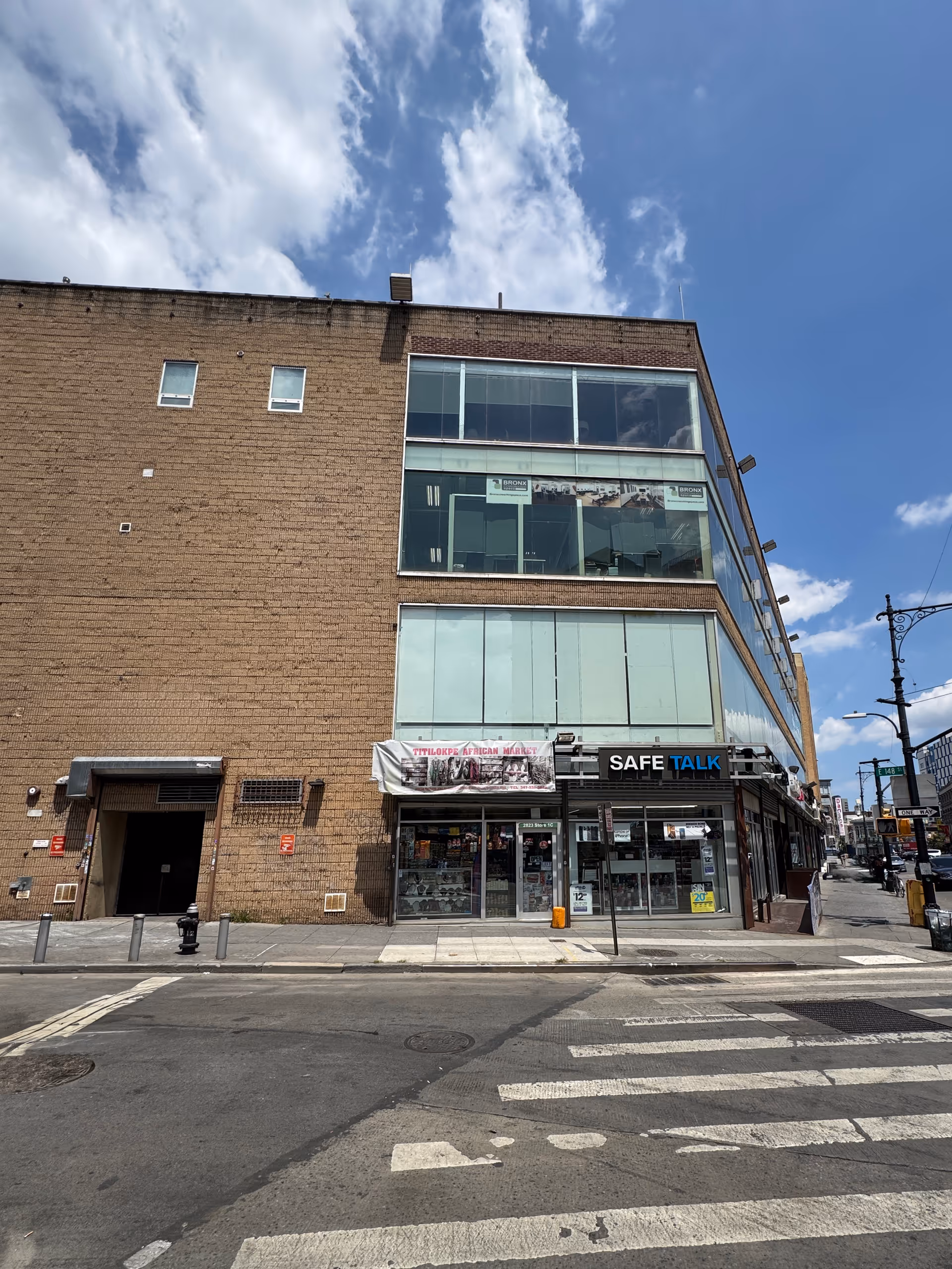 Exterior view of a brick building with large storefront windows and a crosswalk in front