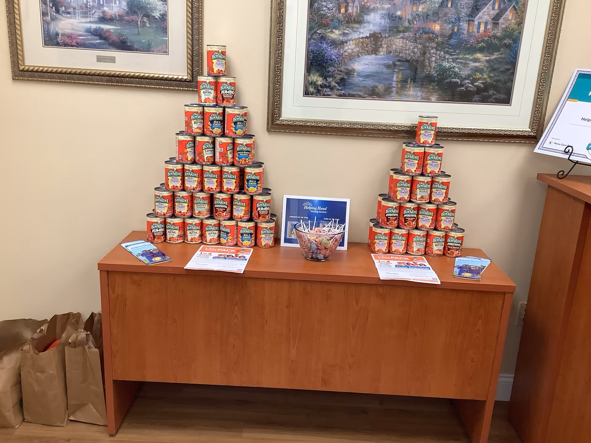 Indoor lobby with tall stacks of canned goods on a wooden cabinet.