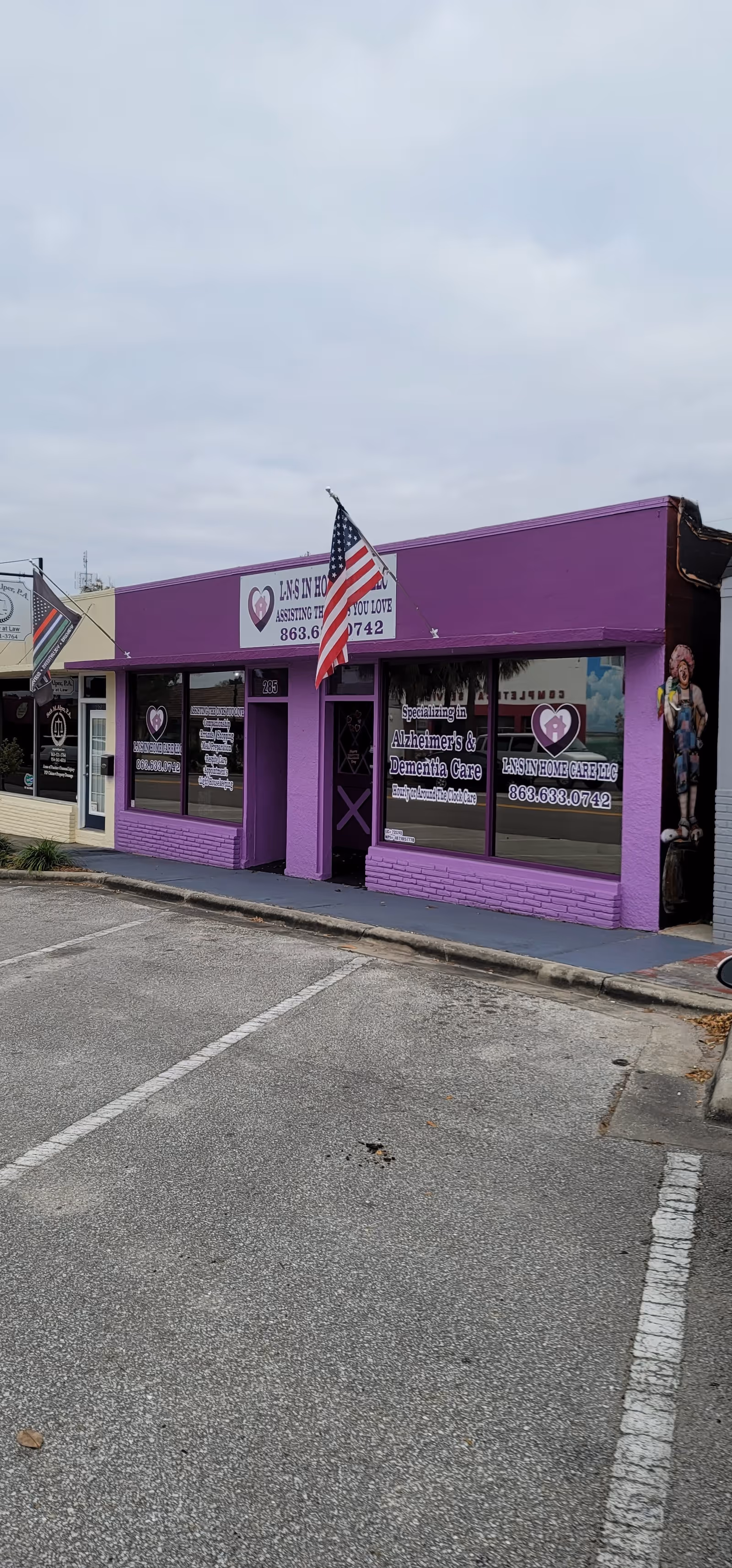 Purple storefront for L-N-S In Home Care LLC with an American flag in front.